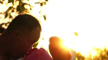  Kırmızı boks eldivenli adam arka planda gün batımında antrenman yapıyor. 