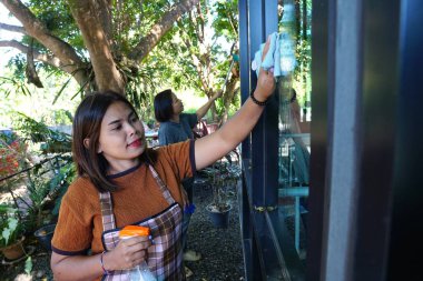 Dışarıdaki pencereyi temizleyen iki Asyalı kadının portresi..