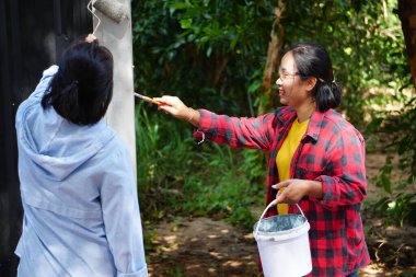 Siyah metal çit boyayan Asyalı kadınlar.