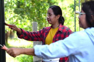 Siyah metal çit boyayan Asyalı kadınlar.