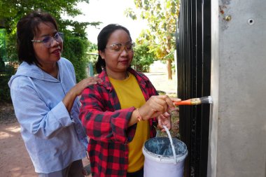 Siyah metal çit boyayan Asyalı kadınlar.