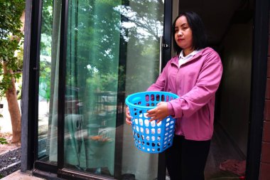 Kapının önünde mavi sepet taşıyan genç bir kadın.