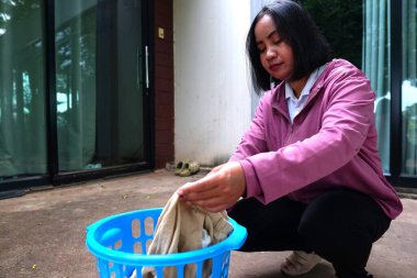 Asyalı kadın sepetin yakınından kıyafet alıyor..