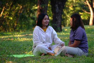 Dışarıda çimenlerde oturan iki kadın..