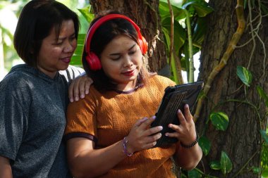 Asyalı kadınlar birlikte tablete bakıyorlar.