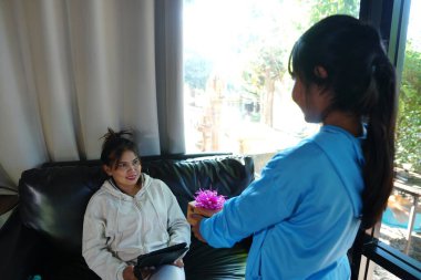 Asyalı Kız, annesine evde çiçek sunuyor.