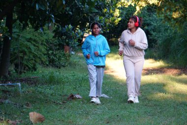 Asyalı kadın ve kız yeşil ormanda oynuyorlar.