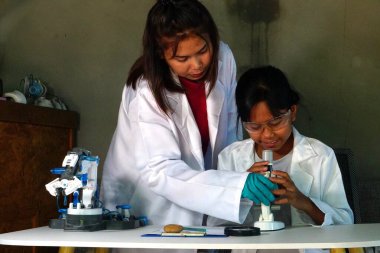 Laboratuvarda Asyalı bir kadın kıza yardım ediyor..