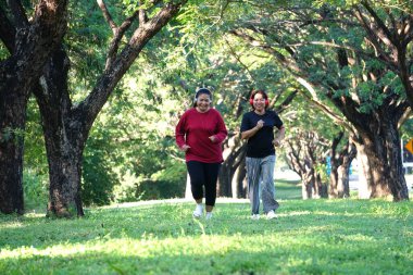 Parkta birlikte koşan Asyalı kadınlar.