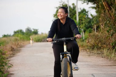 Kırsalda bisiklet süren Asyalı kadın.