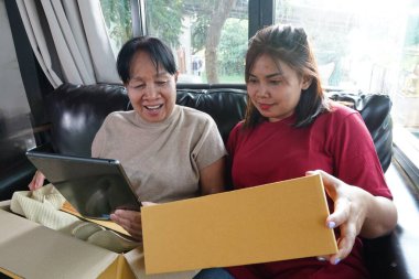 Tablet bilgisayarlı iki kadın kanepeye eşya bırakıyor..