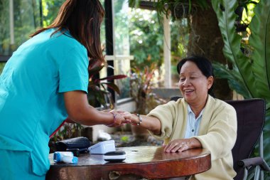 Yaşlı bir kadının kalp atışlarını kontrol etmek için steteskop kullanan bir hemşire..
