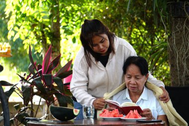 İki kadın dışarıda masada karpuzla oturuyor.