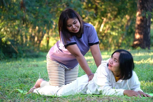 Asyalı kadın yoga minderinde yüzüstü yatan arkadaşına masaj yapıyor..