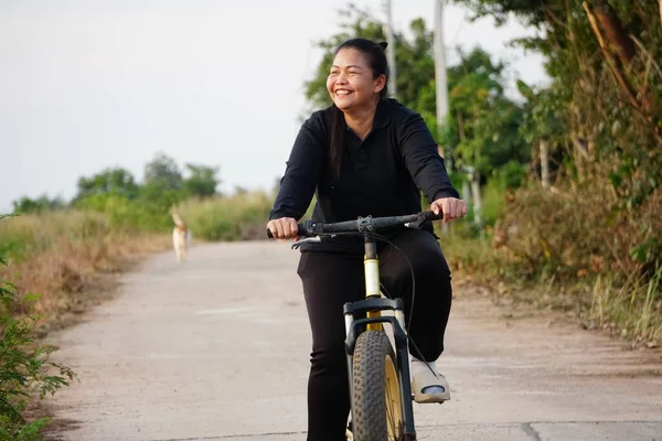 Kırsalda bisiklet süren Asyalı kadın.