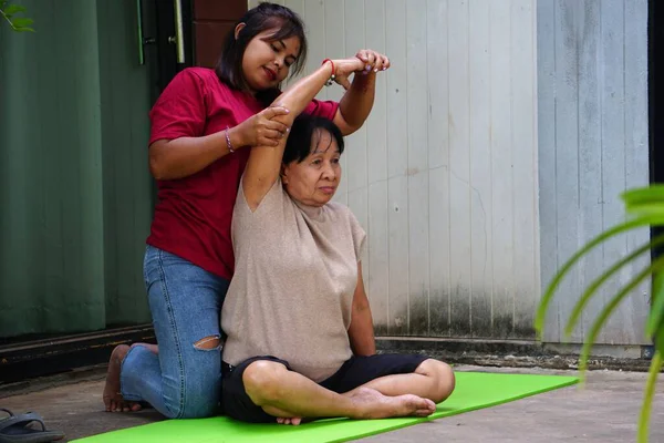 İki Asyalı kadın dışarıda yoga yapıyor.