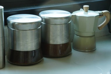 Konteynırlar ve kahve makineleri masanın üstünde.