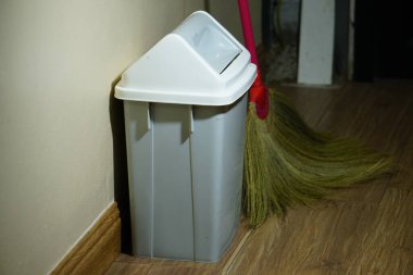 gri plastik çöp kovası ve süpürgesi duvara dayanıyor..