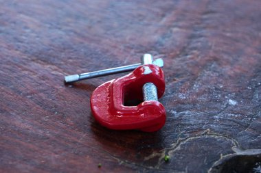 Tahta yüzeyde duran kırmızı klemp aracı.