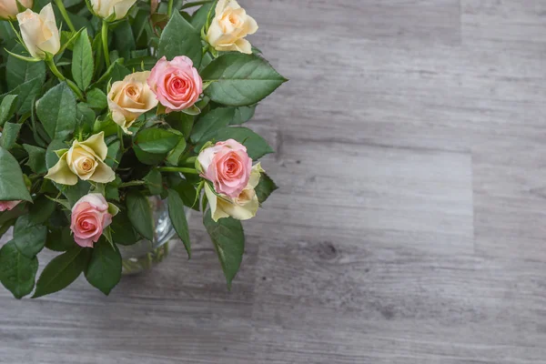 在木桌的粉红色和黄色的玫瑰花束 — 图库照片
