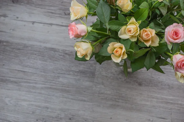 Ramo de rosas rosadas y amarillas sobre mesa de madera —  Fotos de Stock