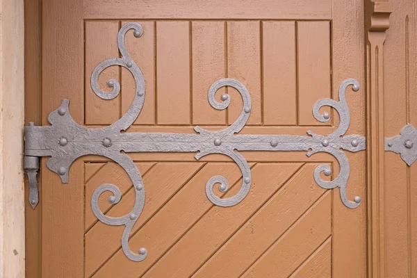 Dobradiça de ferro ornamental em uma porta de madeira velha — Fotografia de Stock