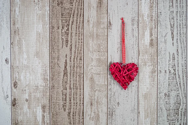 Corazón de madera roja colgando sobre fondo de madera — Foto de Stock