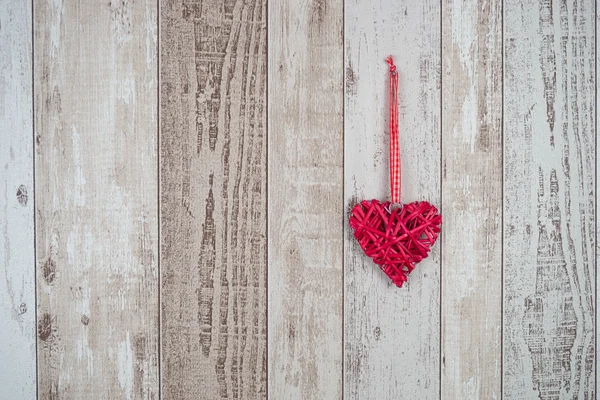 Corazón de madera roja colgando sobre fondo de madera — Foto de Stock