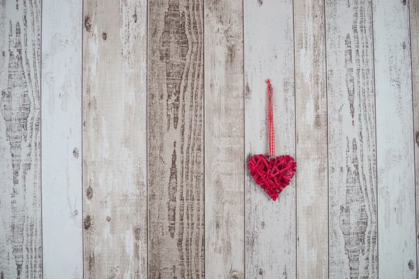 Corazón de madera roja colgando sobre fondo de madera — Foto de Stock