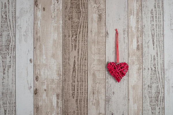 Corazón de madera roja colgando sobre fondo de madera — Foto de Stock