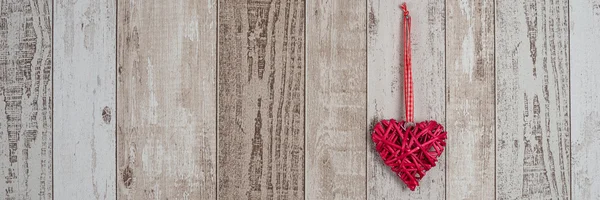 Corazón de madera roja colgando sobre fondo de madera — Foto de Stock