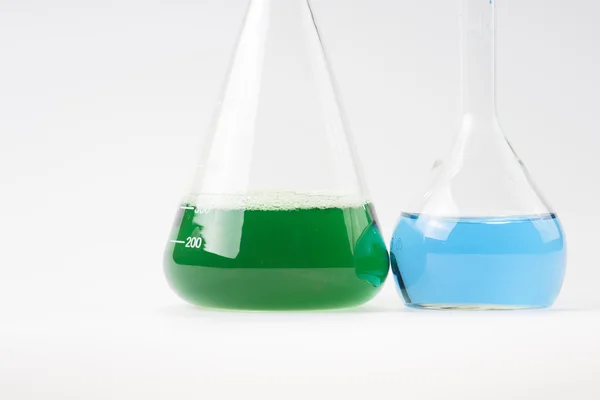 Glass laboratory apparatus with green and blue water — Stock Photo, Image