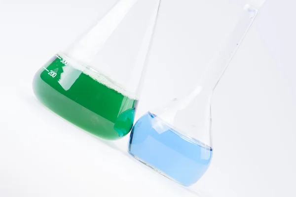 Glass laboratory apparatus with green and blue water — Stock Photo, Image