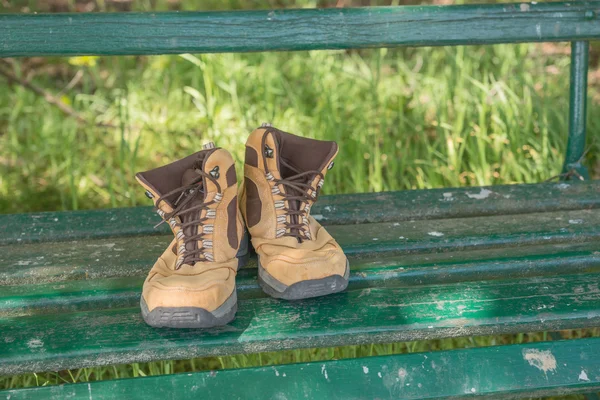 Hiking shoes on green bench — Stock Photo, Image