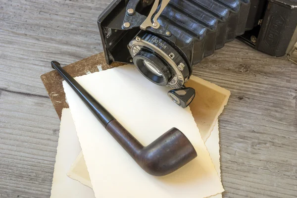 Câmera retro velha com tubo de tabaco na placa de madeira — Fotografia de Stock