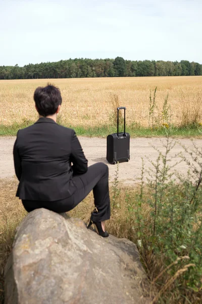 Geschäftsfrau wartet mit Koffer — Stockfoto