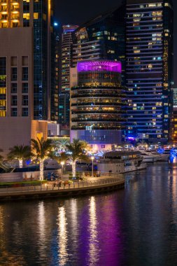 Dubai Marina ufuk çizgisine gece görüşü, Pier 7 ve botları gösteriyor. Turistler ve sakinleri için lüks bir yer. İnanılmaz renkler suyu yansıtıyor..