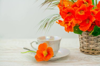 Beyaz arka planda turuncu çiçekler ve bir fincan kahve. 