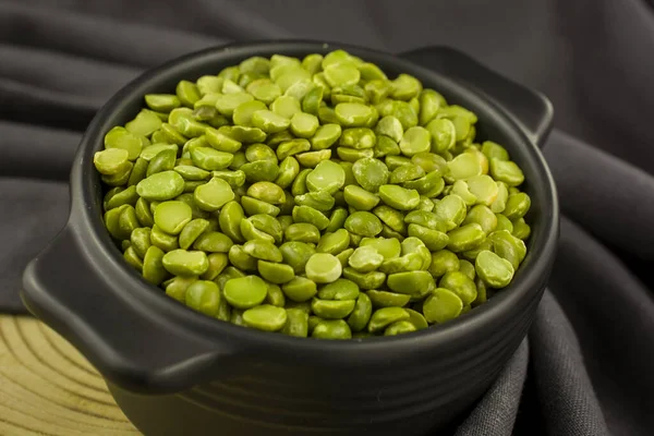 Dried green split peas in a ceramic bowl  on gray background.