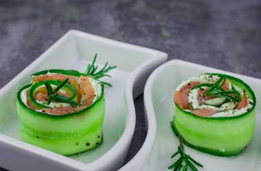 Salatalıklı füme somon ve beyaz tabakta yumuşak peynirli rulo.