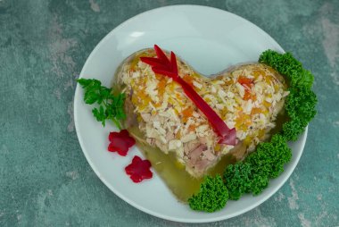 Beyaz tabakta maydanozlu ev yapımı et jölesi. 