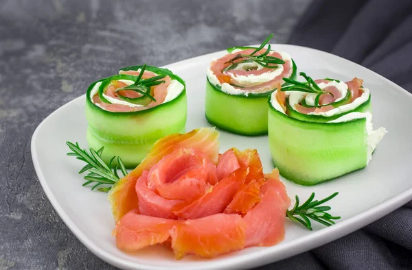 Salatalıklı füme somon ve beyaz tabakta yumuşak peynirli rulo.