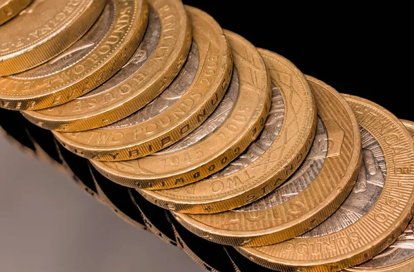 Pile of  UK money gold coin on black background