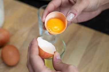 Yumurta sarısını yumurta beyazından ayırıyorum. Mutfakta tabağın hazırlanması. Görünür eller.