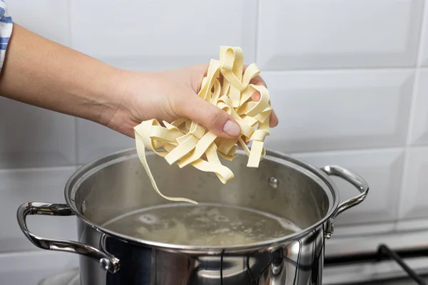 Kaynar suya makarna atan kişi. Bir İtalyan yemeğinin hazırlanması.