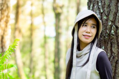 Asyalı kadın çam ağaçlarına yaslanıyor. Banyo yapan ormanın (shinrin-yoku, mandi hutan) tadını çıkarıyorum. Stresi azaltmak, kan basıncını düşürmek ve bağışıklığı arttırmak için sağlık yöntemleri.