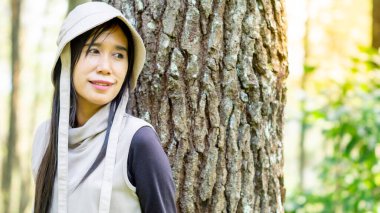 Asyalı kadın çam ağaçlarına yaslanıyor. Banyo yapan ormanın (shinrin-yoku, mandi hutan) tadını çıkarıyorum. Stresi azaltmak, kan basıncını düşürmek ve bağışıklığı arttırmak için sağlık yöntemleri.