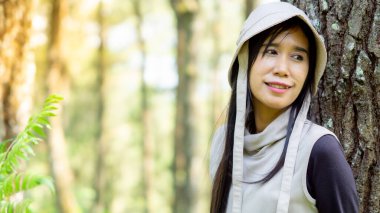 Asyalı kadın çam ağaçlarına yaslanıyor. Banyo yapan ormanın (shinrin-yoku, mandi hutan) tadını çıkarıyorum. Stresi azaltmak, kan basıncını düşürmek ve bağışıklığı arttırmak için sağlık yöntemleri.