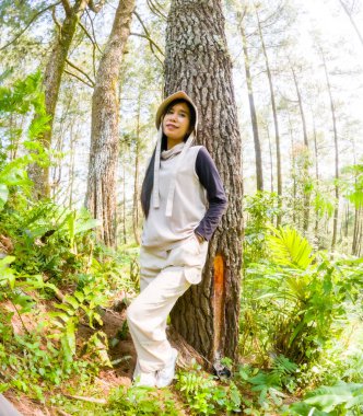 Asyalı bir kadın çam ağacına yaslanıyor, Japon banyo ormanı uyguluyor.