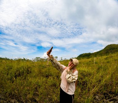 Beautiful Asian selfie at meadow with mountain and blue sky